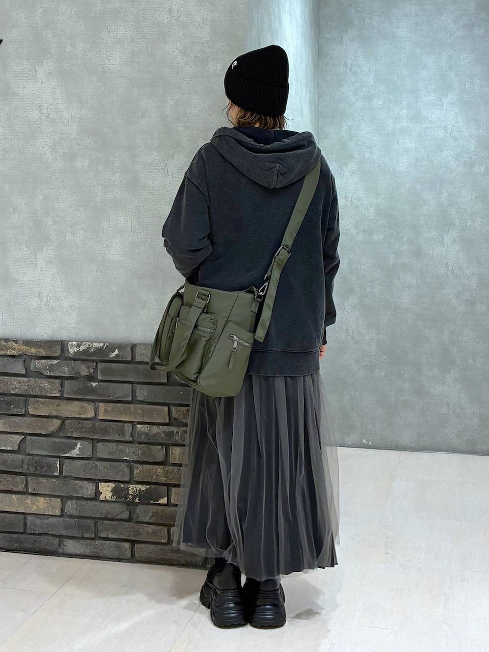 ブラック系のブーツ、グリーン系のボストンバッグ、ブラック系のパーカーを着用したレディースの秋コーディネートの4枚目の写真