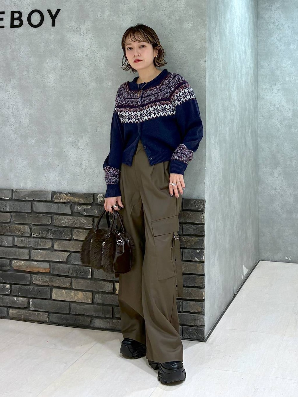 ブラック系のスニーカー、ブラウン系のスラックス、ブラウン系のボストンバッグを着用したレディースの冬コーディネートの6枚目の写真