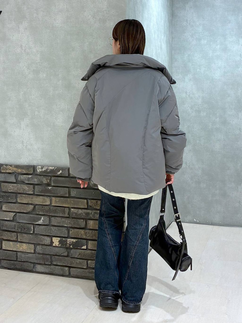 ブラック系のスニーカー、ブルー系のデニムパンツ、グレー系のブルゾンを着用したレディースの冬コーディネートの5枚目の写真