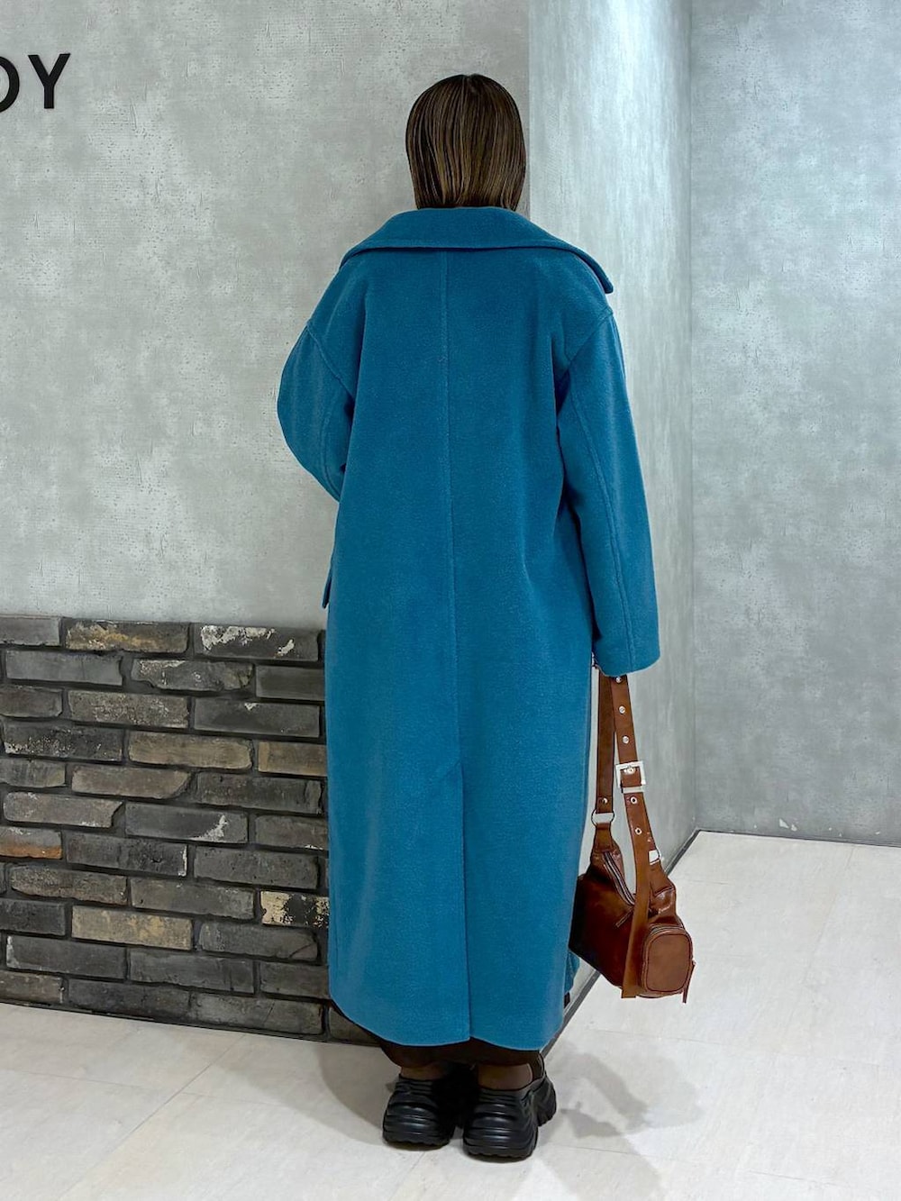 ブラウン系のブーツ、グリーン系のチェスターコート、ブラウン系のニット/セーターを着用したレディースの冬コーディネートの3枚目の写真