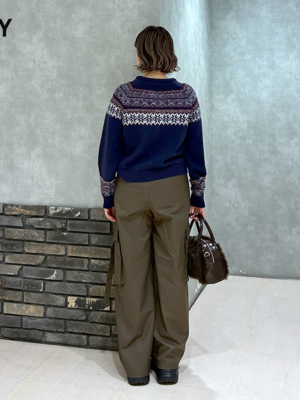 ブラック系のスニーカー、ブラウン系のスラックス、ブラウン系のボストンバッグを着用したレディースの冬コーディネートの4枚目の写真