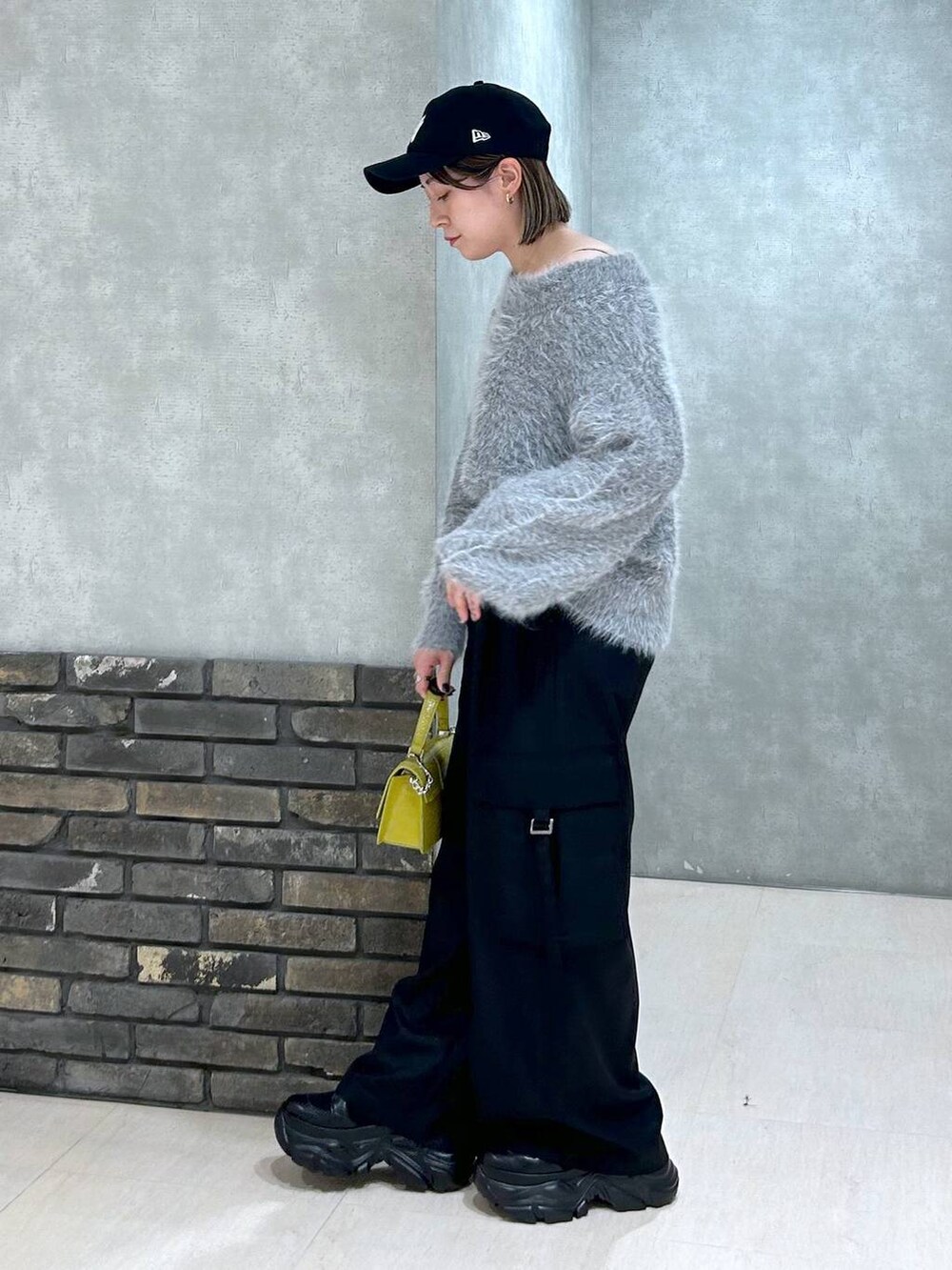 ブラック系のブーツ、イエロー系のハンドバッグ、ブラック系のスラックスを着用したレディースの秋コーディネートの5枚目の写真