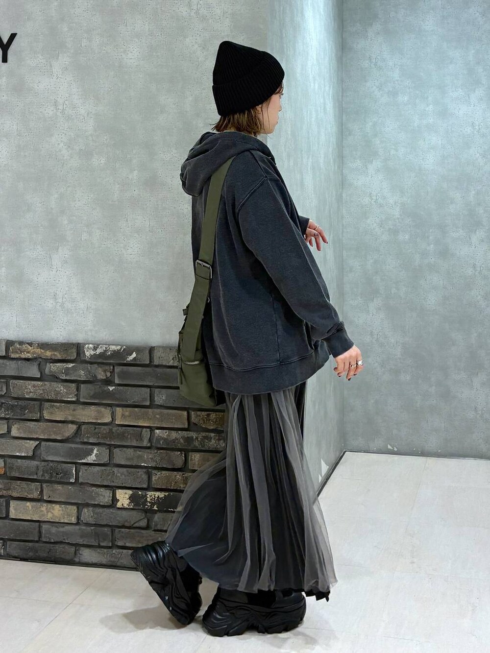 ブラック系のブーツ、グリーン系のボストンバッグ、ブラック系のパーカーを着用したレディースの秋コーディネートの3枚目の写真