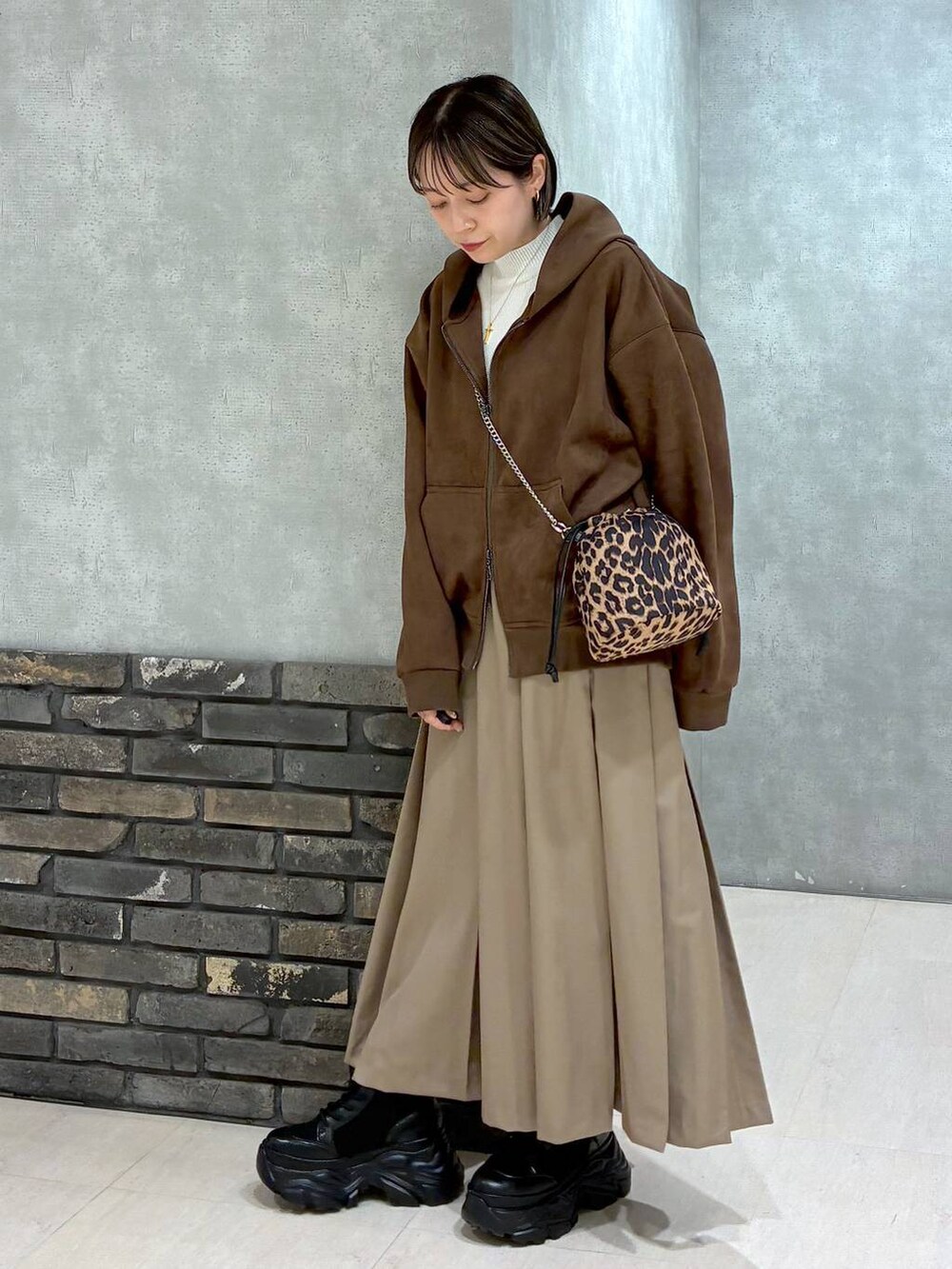 ブラック系のブーツ、ブラウン系のパーカー、ベージュ系のスカートを着用したレディースの冬コーディネートの5枚目の写真