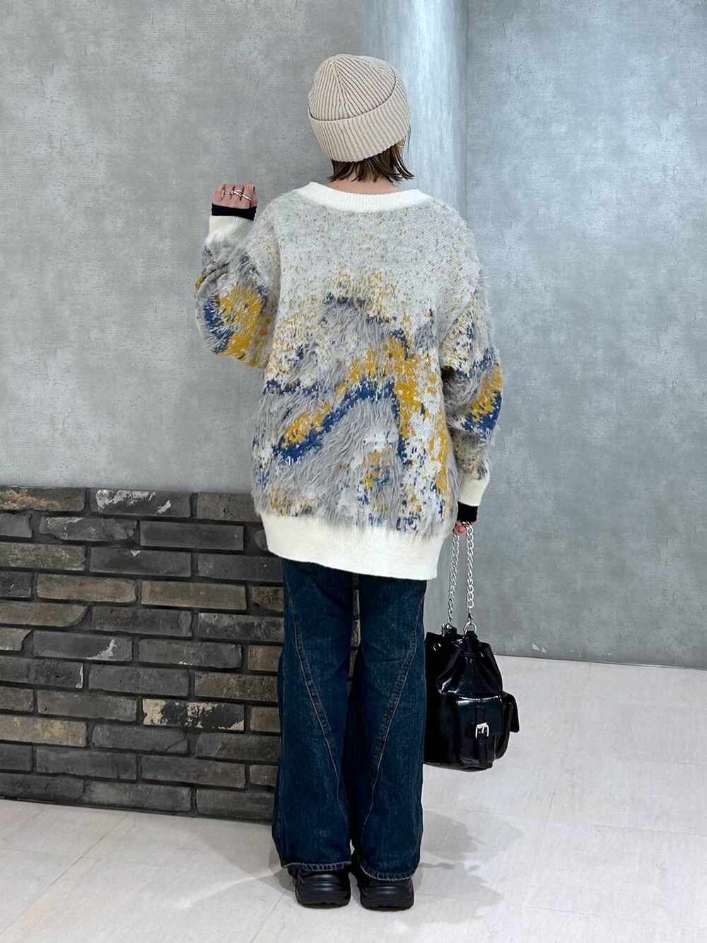 ブラック系のスニーカー、ブルー系のデニムパンツ、ブラック系のショルダーバッグを着用したレディースの秋コーディネートの6枚目の写真