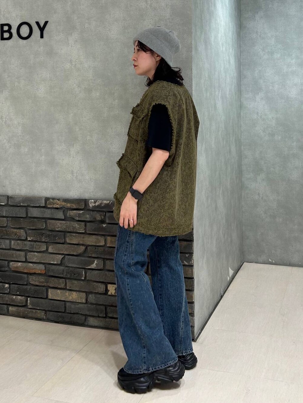 ブラック系のスニーカー、ブラック系のTシャツ/カットソー、ブルー系のデニムパンツを着用したレディースの秋コーディネートの3枚目の写真