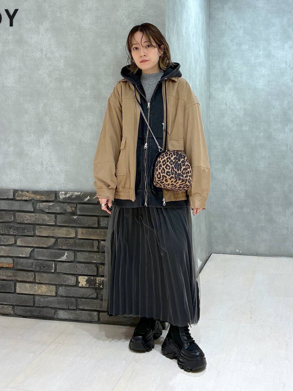 ブラック系のブーツ、イエロー系のブルゾン、ブラック系のパーカーを着用したレディースの秋コーディネートの2枚目の写真