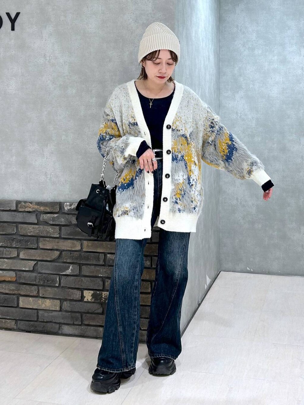 ブラック系のスニーカー、ブルー系のデニムパンツ、ブラック系のショルダーバッグを着用したレディースの秋コーディネートの4枚目の写真