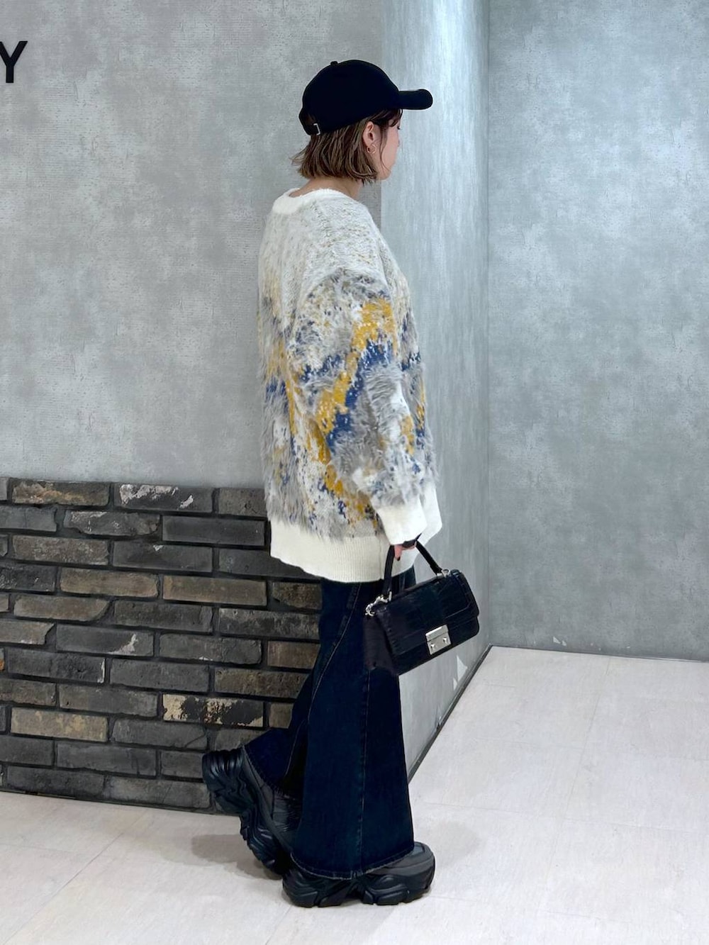 グレー系のスニーカー、ブルー系のデニムパンツ、ブラック系のハンドバッグを着用したレディースの秋コーディネートの3枚目の写真