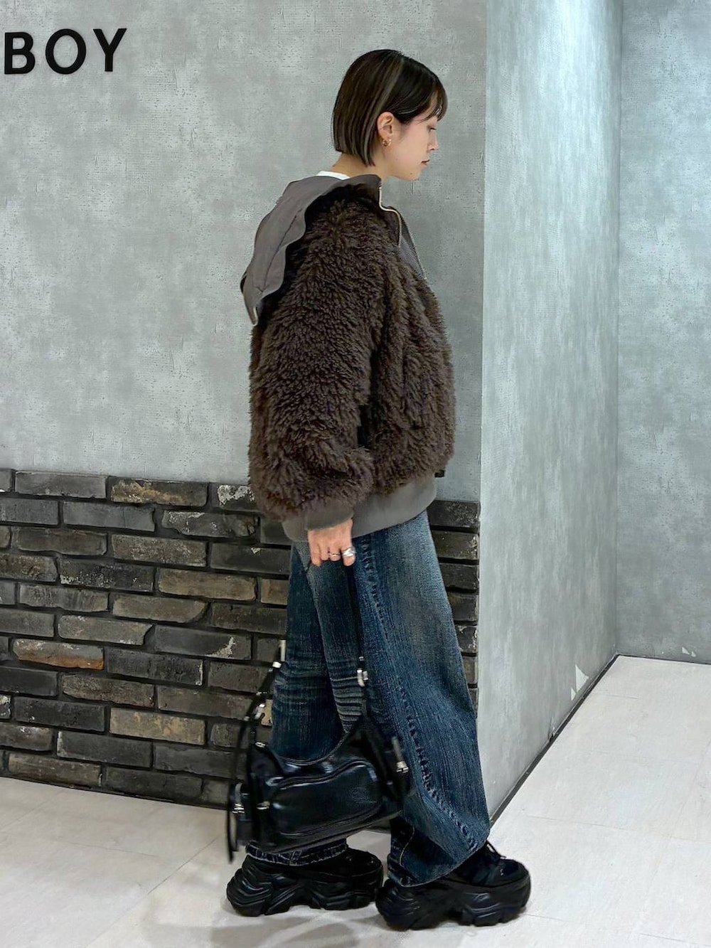 ブラック系のスニーカー、ブラウン系のブルゾン、ブラック系のショルダーバッグを着用したレディースの秋コーディネートの4枚目の写真