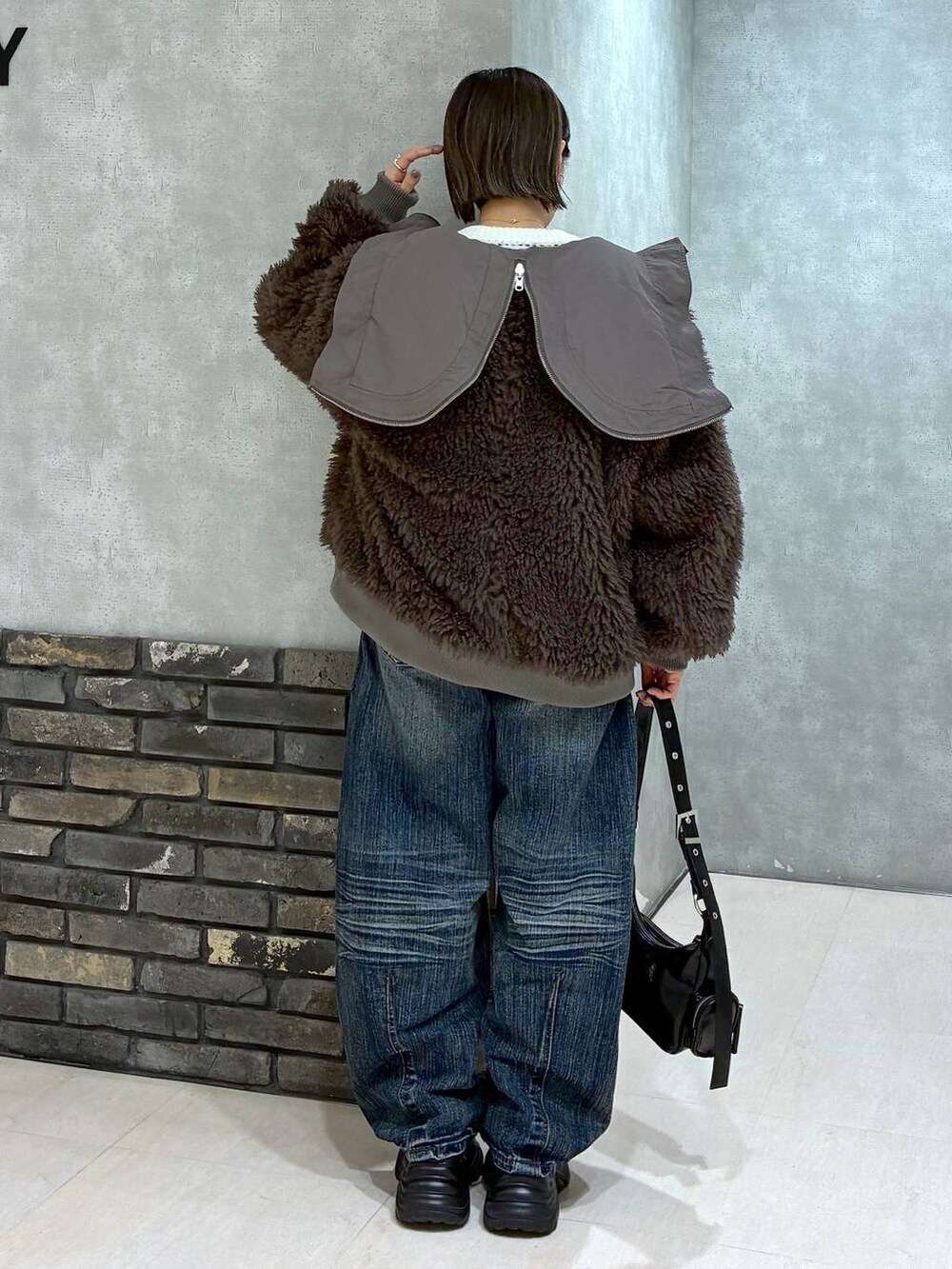 ブラック系のスニーカー、ブラウン系のブルゾン、ブラック系のショルダーバッグを着用したレディースの秋コーディネートの5枚目の写真