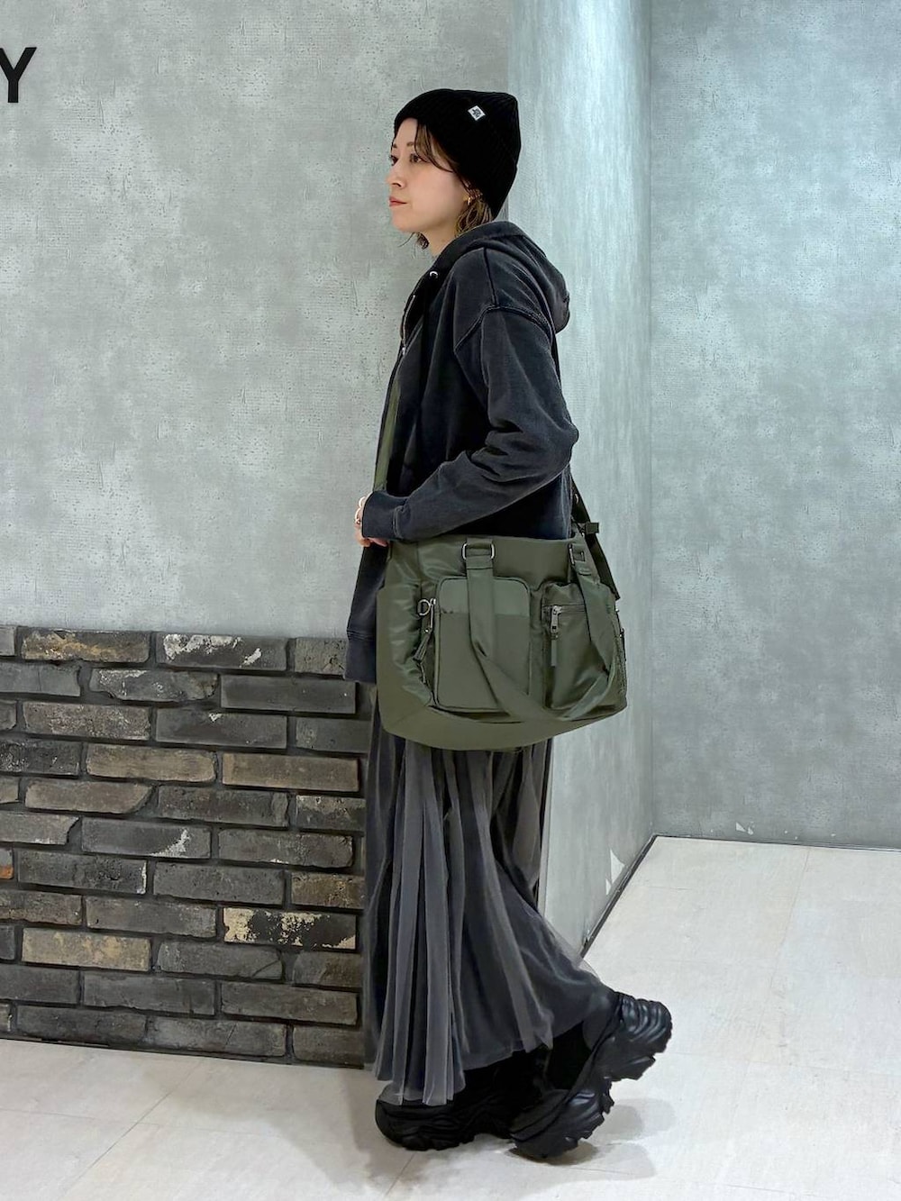 ブラック系のブーツ、グリーン系のボストンバッグ、ブラック系のパーカーを着用したレディースの秋コーディネートの6枚目の写真