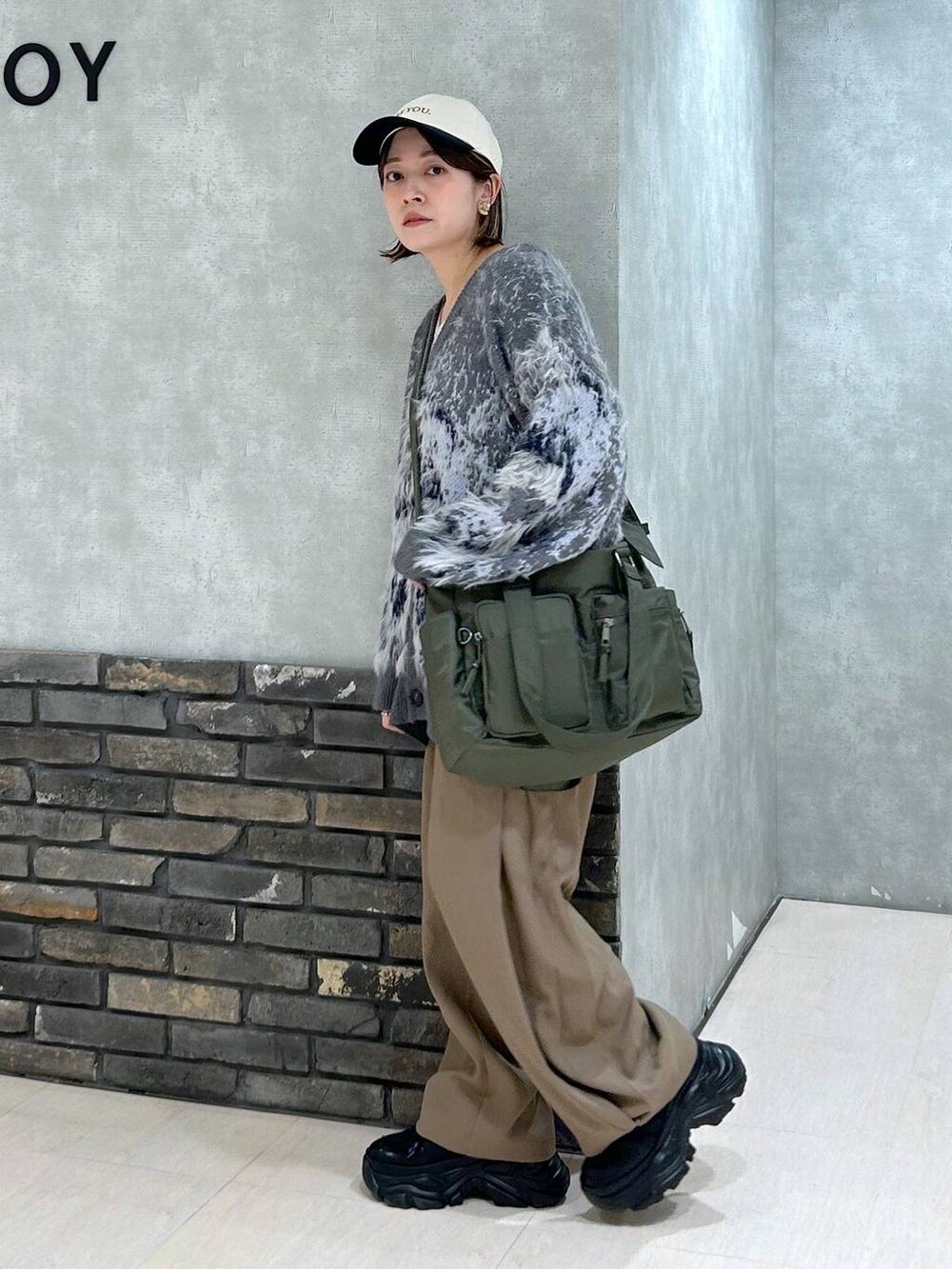 ブラック系のスニーカー、グリーン系のボストンバッグ、グレー系のカーディガン/ボレロを着用したレディースの秋コーディネートの7枚目の写真