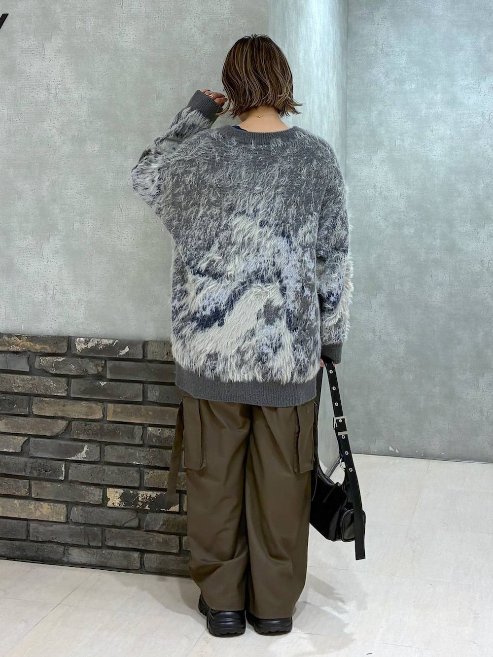 グレー系のスニーカー、ブラウン系のスラックス、グリーン系のニット/セーターを着用したレディースの冬コーディネートの4枚目の写真