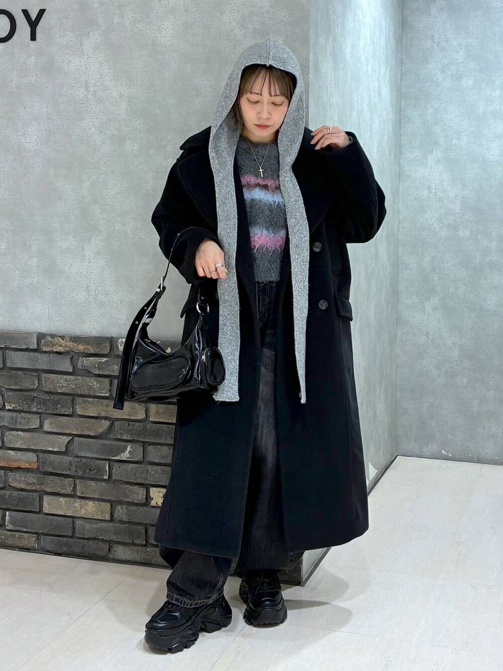 ブラック系のスニーカー、ブラック系のチェスターコート、ブラック系のデニムパンツを着用したレディースの冬コーディネートの2枚目の写真