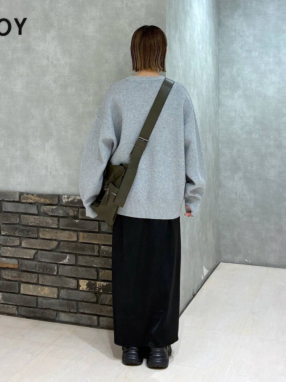 グレー系のスニーカー、グリーン系のボストンバッグ、グレー系のニット/セーターを着用したレディースの冬コーディネートの4枚目の写真