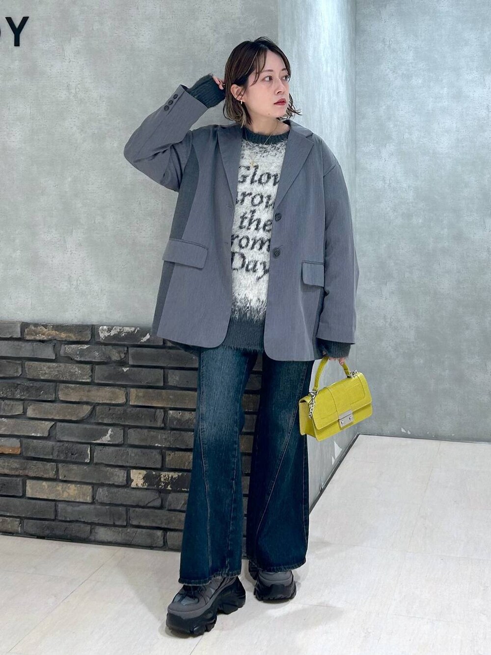 グレー系のスニーカー、ブルー系のデニムパンツ、グレー系のテーラードジャケットを着用したレディースの秋コーディネートの6枚目の写真