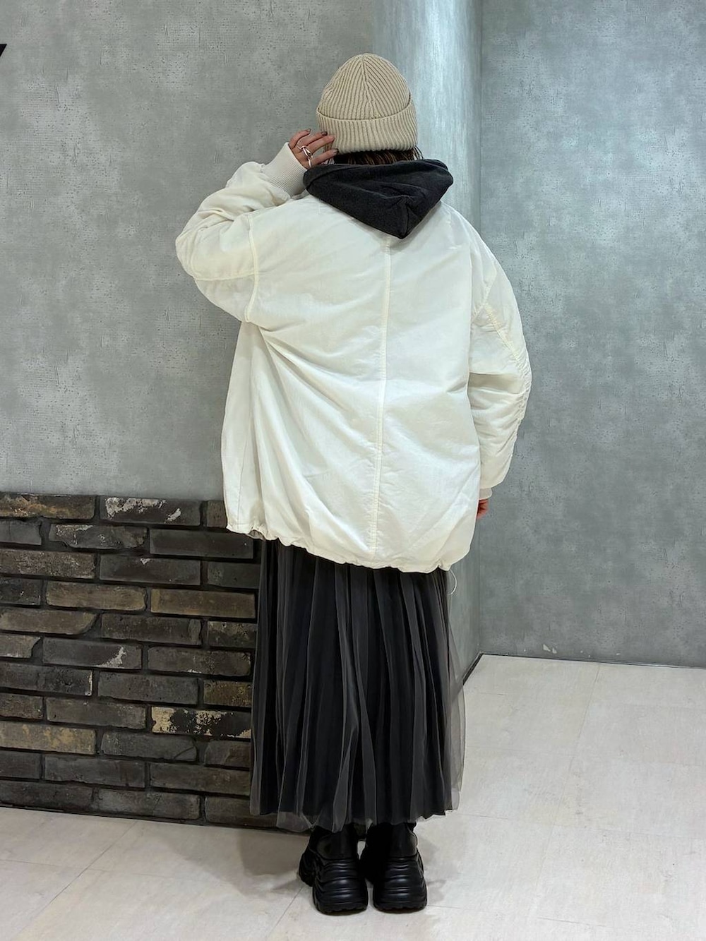 ブラック系のブーツ、ブラック系のパーカー、ホワイト系のブルゾンを着用したレディースの秋コーディネートの4枚目の写真