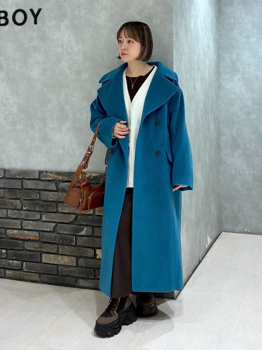 ブラウン系のブーツ、グリーン系のチェスターコート、ブラウン系のニット/セーターを着用したレディースの冬コーディネートの6枚目の写真