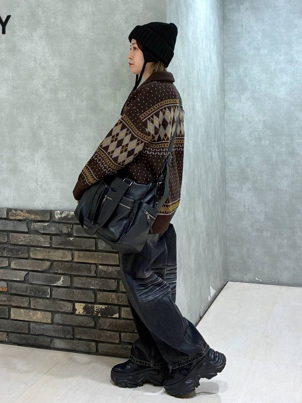 ブラック系のスニーカー、ブラック系のボストンバッグ、ブラック系のデニムパンツを着用したレディースの冬コーディネートの5枚目の写真