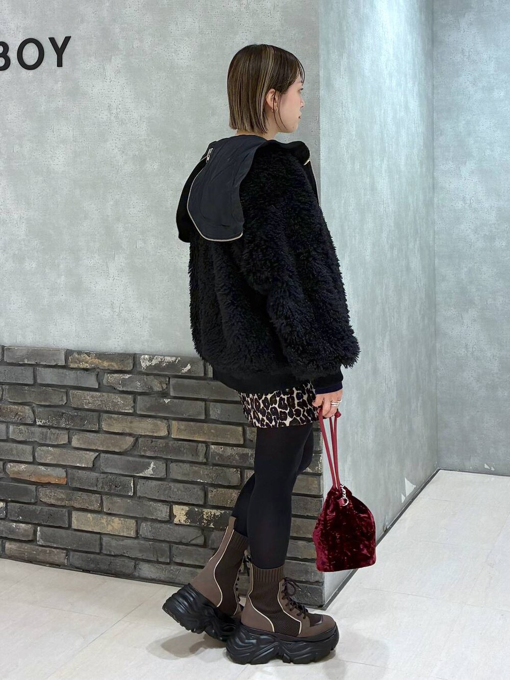 ブラウン系のブーツ、ブラック系のブルゾン、ブラウン系のスカートを着用したレディースの冬コーディネートの2枚目の写真