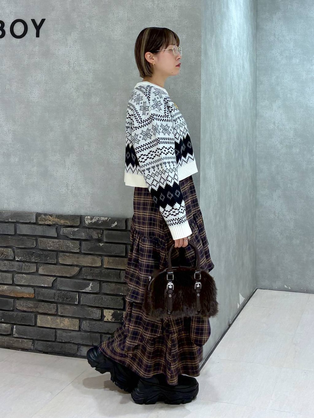 ブラック系のブーツ、ブラウン系のスカート、ブラウン系のボストンバッグを着用したレディースの冬コーディネートの4枚目の写真