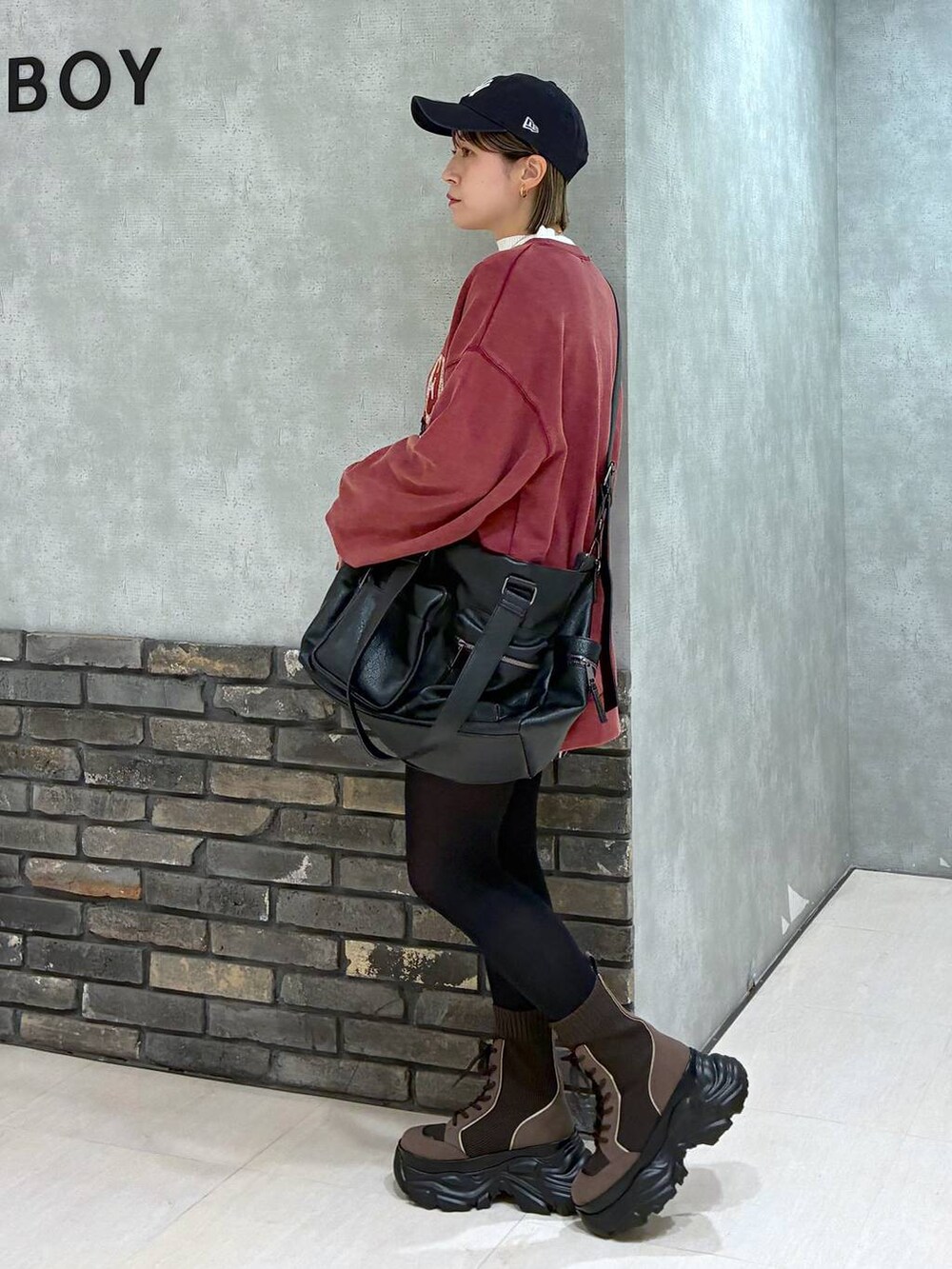 ブラウン系のブーツ、ブラック系のボストンバッグ、レッド系のスウェットを着用したレディースの冬コーディネートの7枚目の写真