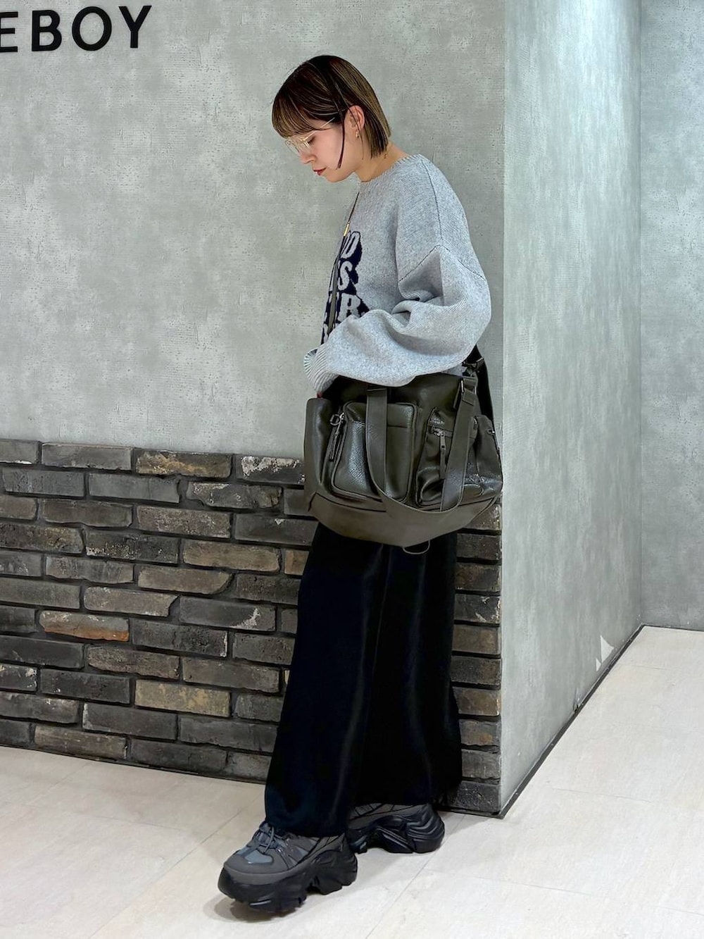 グレー系のスニーカー、グリーン系のボストンバッグ、グレー系のニット/セーターを着用したレディースの冬コーディネートの6枚目の写真