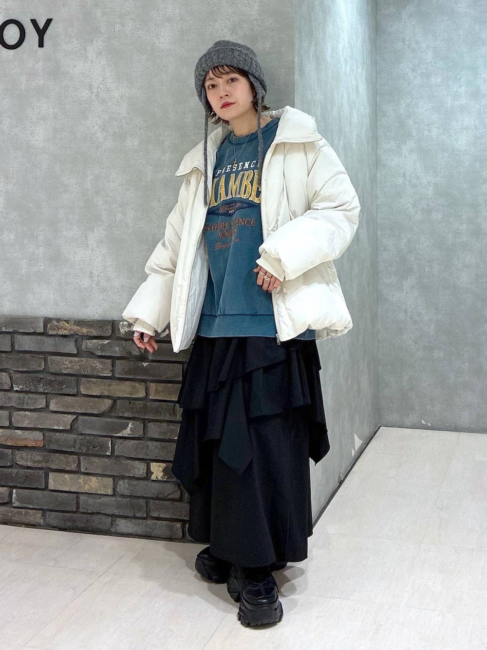 ブラック系のスニーカー、グリーン系のスウェット、ブラック系のスカートを着用したレディースの冬コーディネートの2枚目の写真