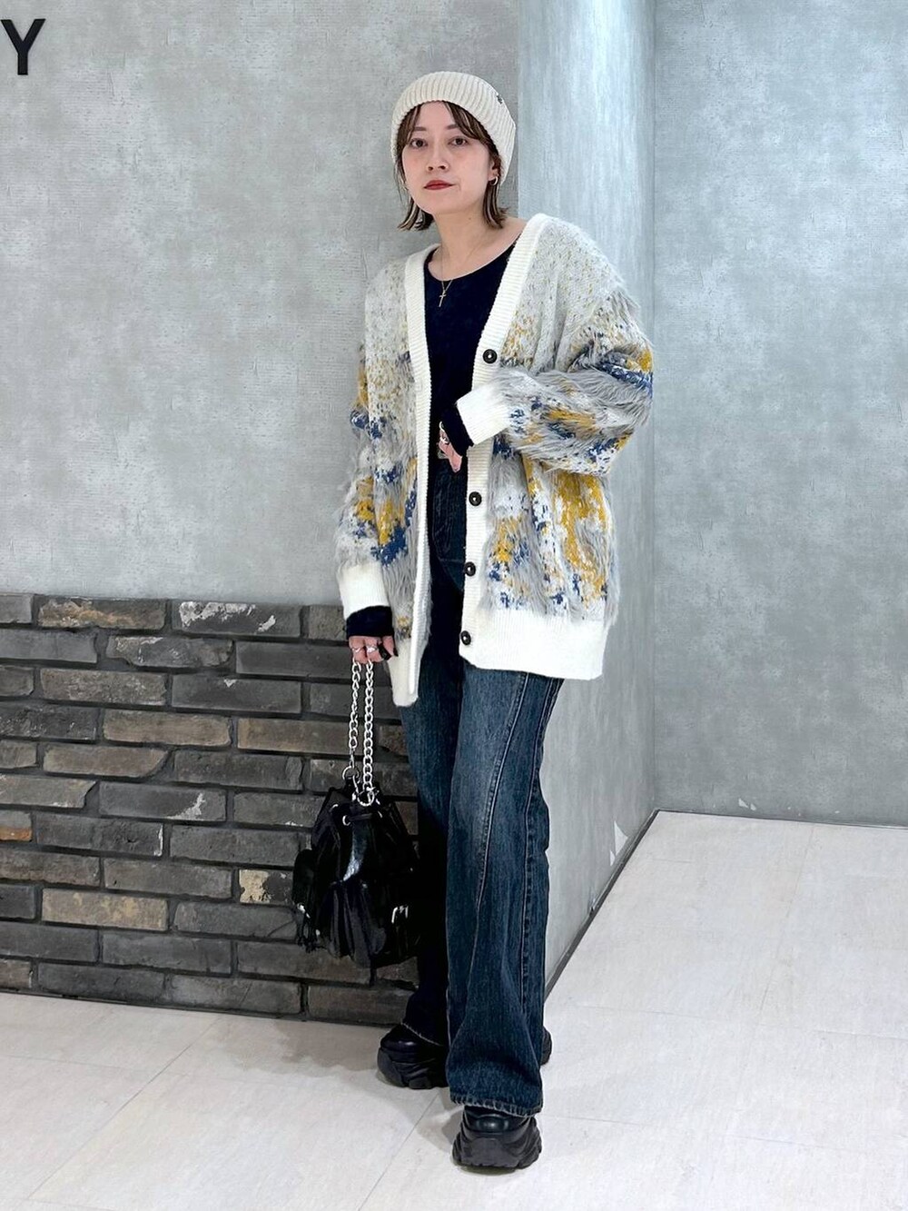 ブラック系のスニーカー、ブルー系のデニムパンツ、ブラック系のショルダーバッグを着用したレディースの秋コーディネートの9枚目の写真