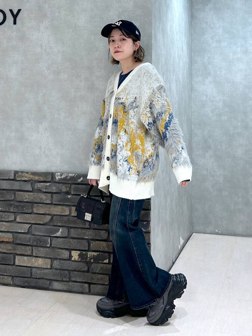 グレー系のスニーカー、ブルー系のデニムパンツ、ブラック系のハンドバッグを着用したレディースの秋コーディネートの7枚目の写真