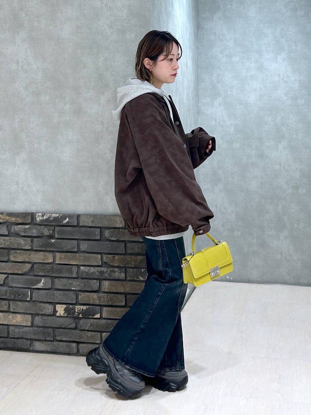 グレー系のスニーカー、ブルー系のデニムパンツ、イエロー系のハンドバッグを着用したレディースの秋コーディネートの3枚目の写真