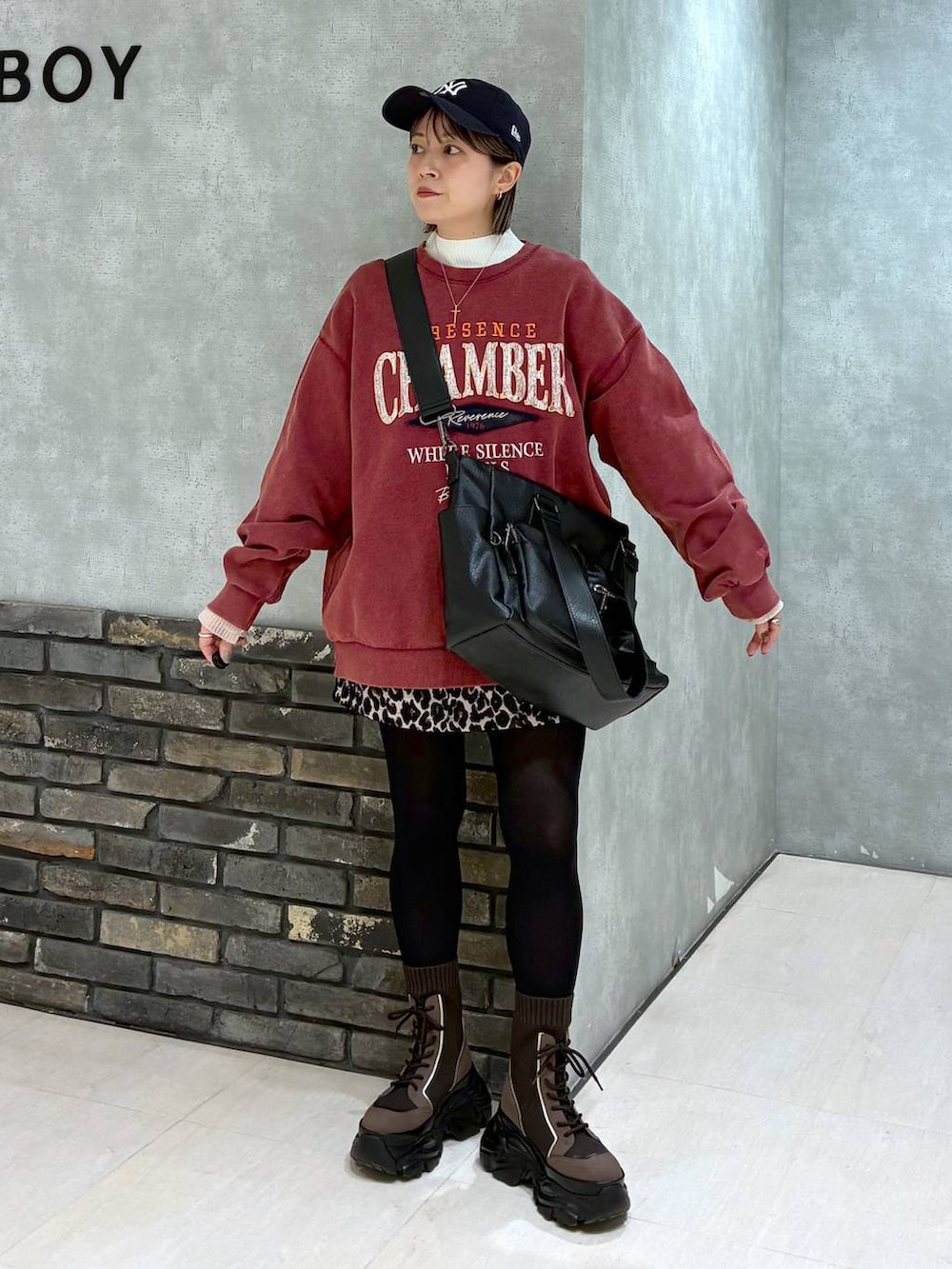 ブラウン系のブーツ、ブラック系のボストンバッグ、レッド系のスウェットを着用したレディースの冬コーディネートの2枚目の写真