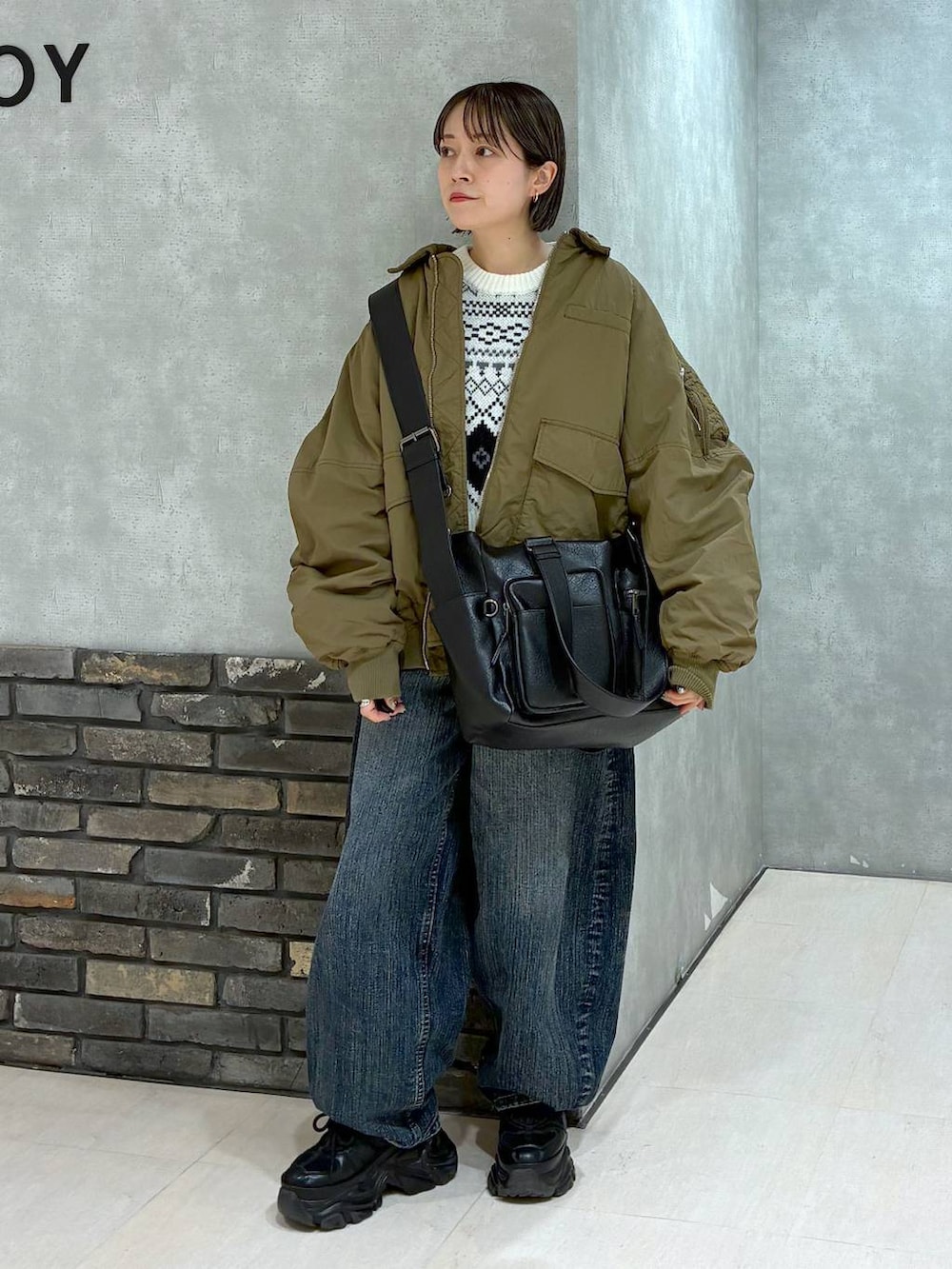 ブラック系のスニーカー、ブラック系のボストンバッグ、ブルー系のデニムパンツを着用したレディースの冬コーディネートの6枚目の写真