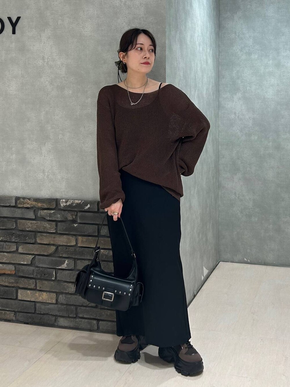 ブラウン系のブーツ、ブラック系のキャミソール、ブラウン系のニット/セーターを着用したレディースの秋コーディネートの2枚目の写真