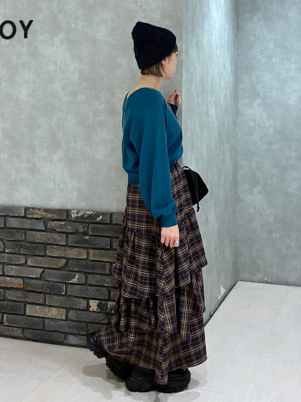 ブラック系のブーツ、ブラウン系のスカート、グリーン系のニット/セーターを着用したレディースの冬コーディネートの2枚目の写真