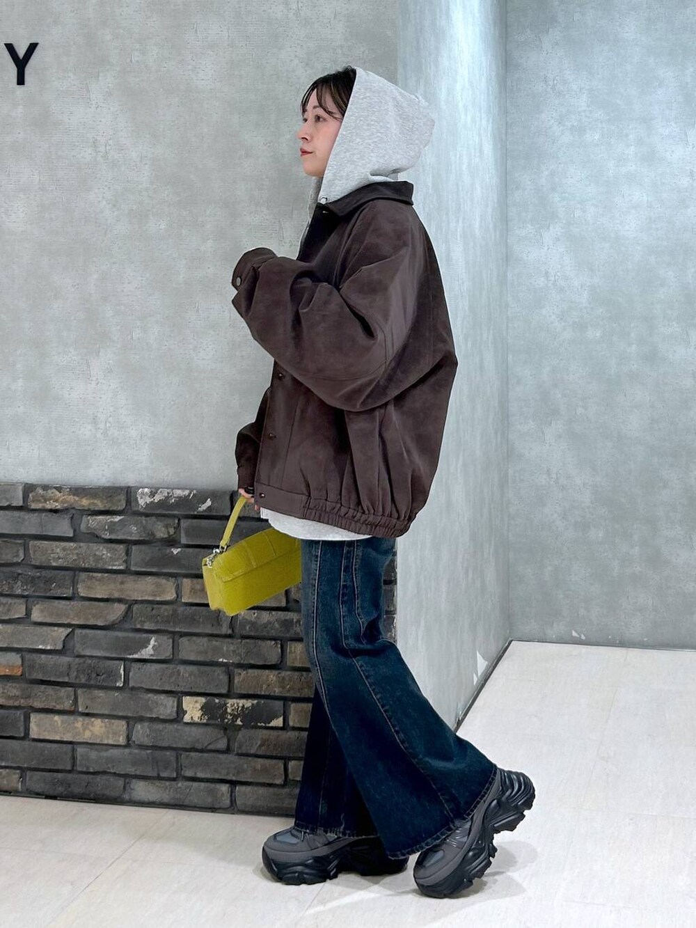 グレー系のスニーカー、ブルー系のデニムパンツ、イエロー系のハンドバッグを着用したレディースの秋コーディネートの6枚目の写真