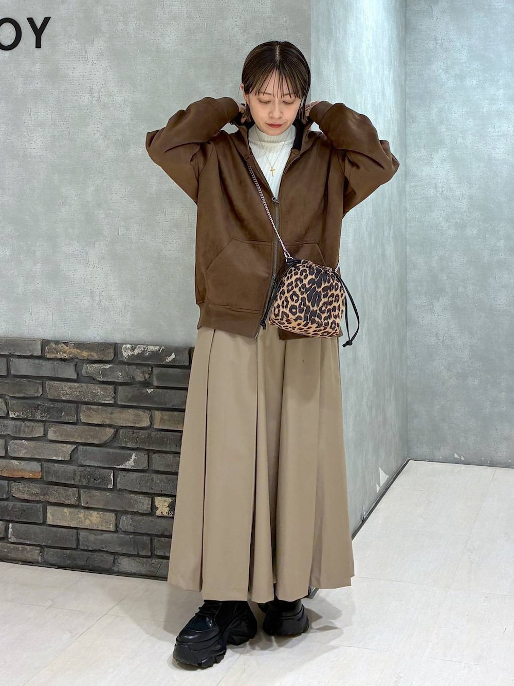 ブラック系のブーツ、ブラウン系のパーカー、ベージュ系のスカートを着用したレディースの冬コーディネートの7枚目の写真