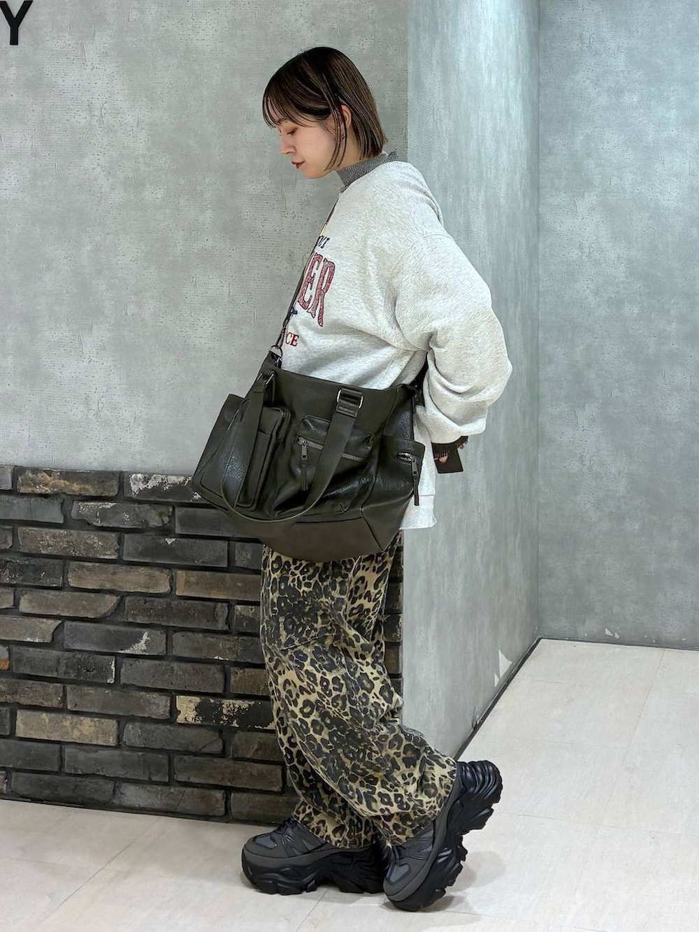 グレー系のスニーカー、グリーン系のボストンバッグ、ベージュ系のスウェットを着用したレディースの冬コーディネートの4枚目の写真