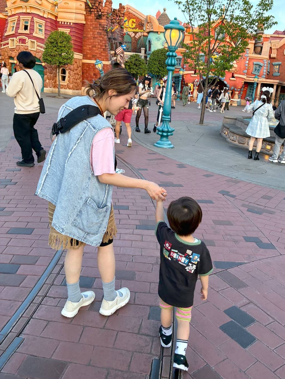 ベージュ系のスカート、ブルー系のベスト、イエロー系のネックレスを着用したレディースの夏コーディネートの4枚目の写真