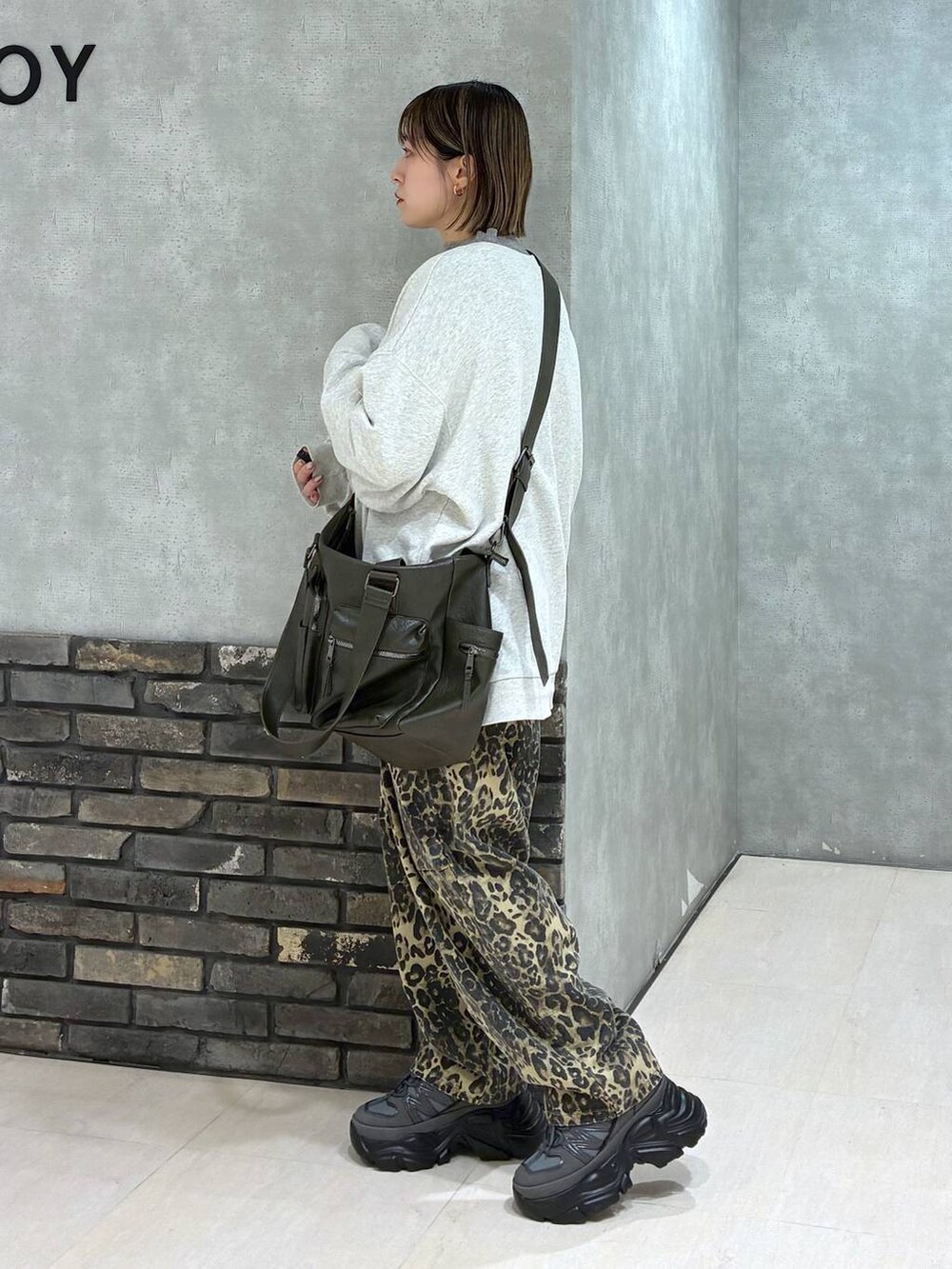 グレー系のスニーカー、グリーン系のボストンバッグ、ベージュ系のスウェットを着用したレディースの冬コーディネートの5枚目の写真