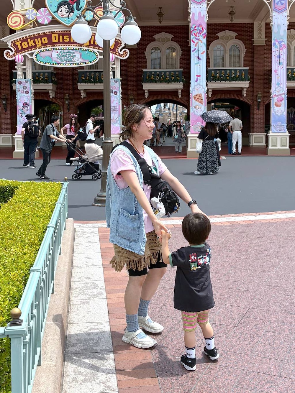 ベージュ系のスカート、ブルー系のベスト、イエロー系のネックレスを着用したレディースの夏コーディネートの2枚目の写真
