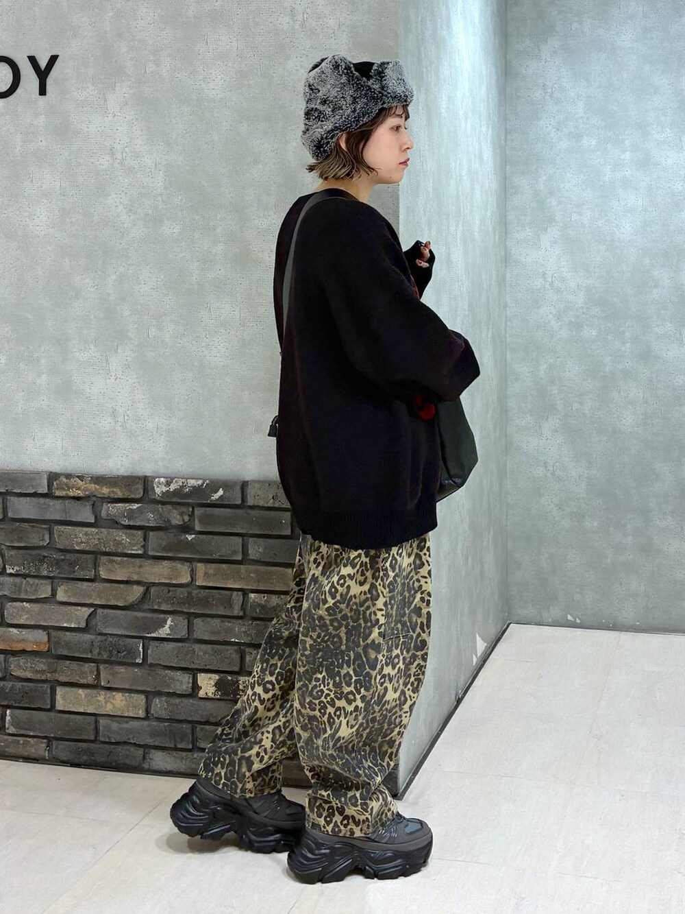 グレー系のスニーカー、ブラック系のボストンバッグ、ブラック系のニット/セーターを着用したレディースの冬コーディネートの3枚目の写真