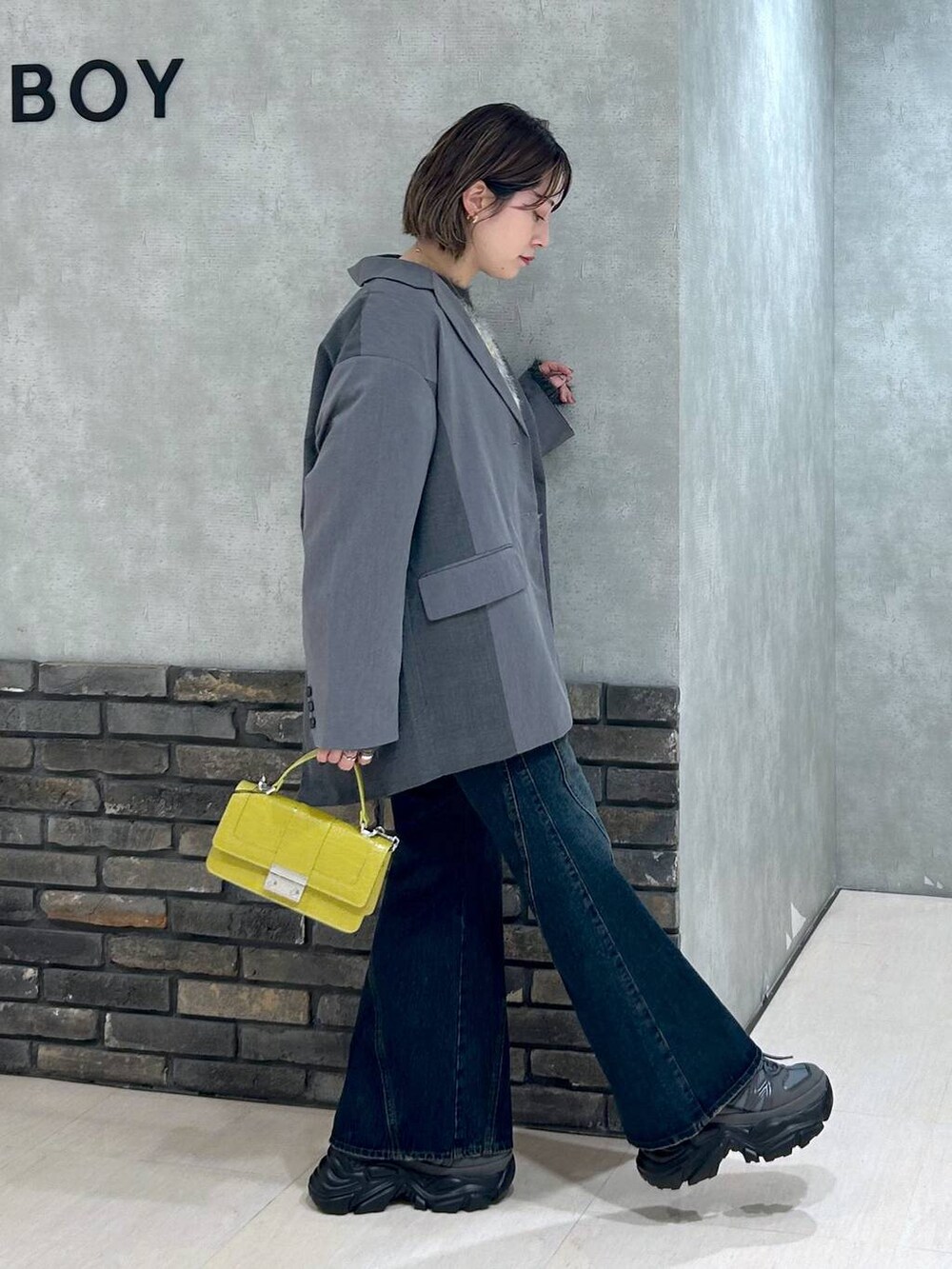 グレー系のスニーカー、ブルー系のデニムパンツ、グレー系のテーラードジャケットを着用したレディースの秋コーディネートの3枚目の写真