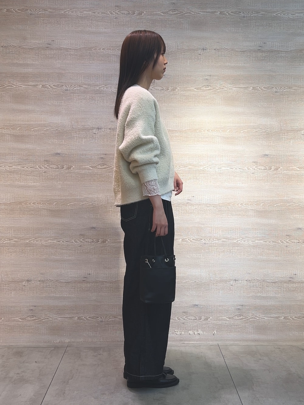 ホワイト系のニット/セーター、ホワイト系のTシャツ/カットソー、ブラック系のトートバッグを着用したレディースの冬コーディネートの2枚目の写真