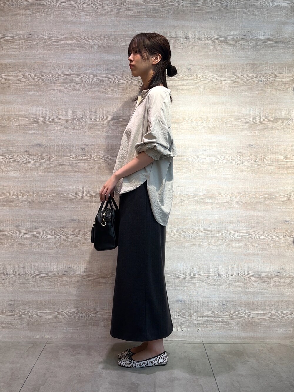 グレー系のシャツ/ブラウス、グレー系のスカート、ブラック系のショルダーバッグを着用したレディースの秋コーディネートの2枚目の写真