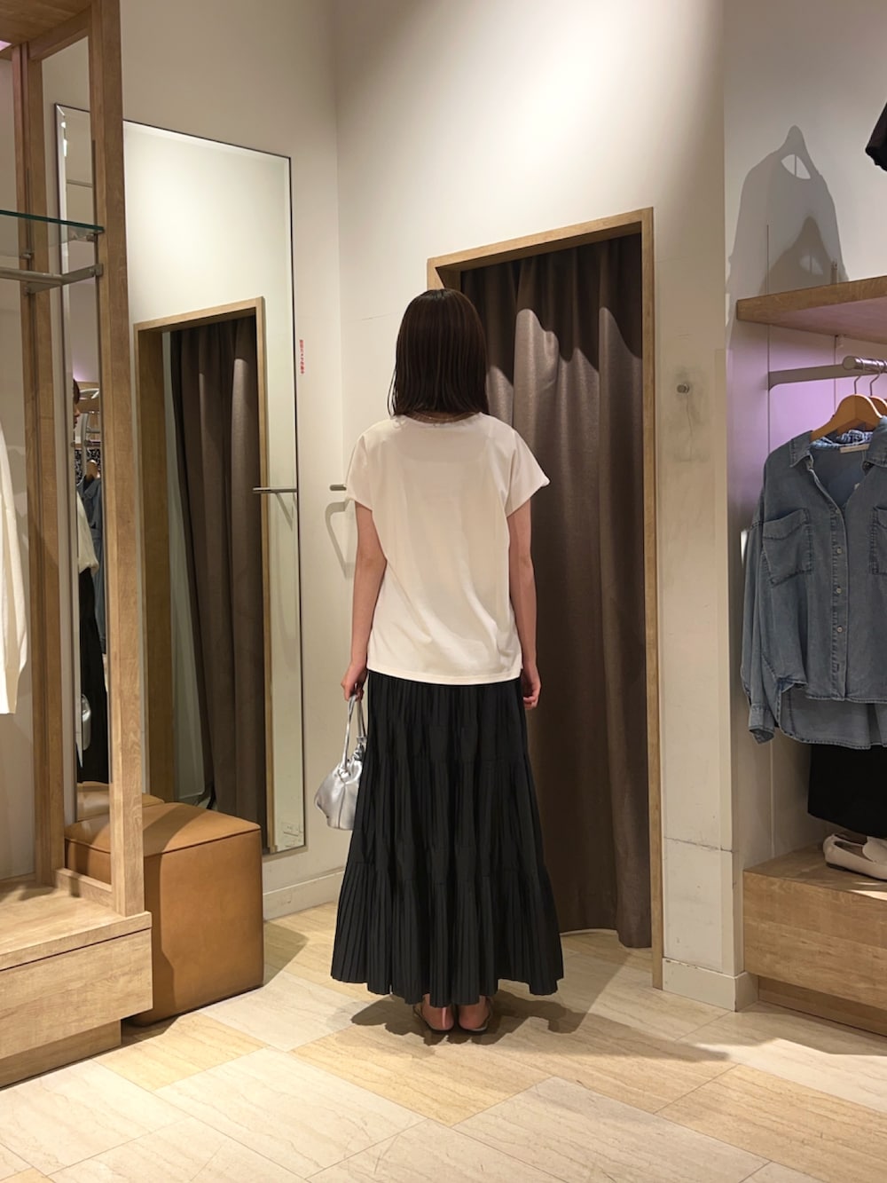 ブラック系のスカート、ホワイト系のTシャツ/カットソー、シルバー系のトートバッグを着用したレディースの夏コーディネートの2枚目の写真