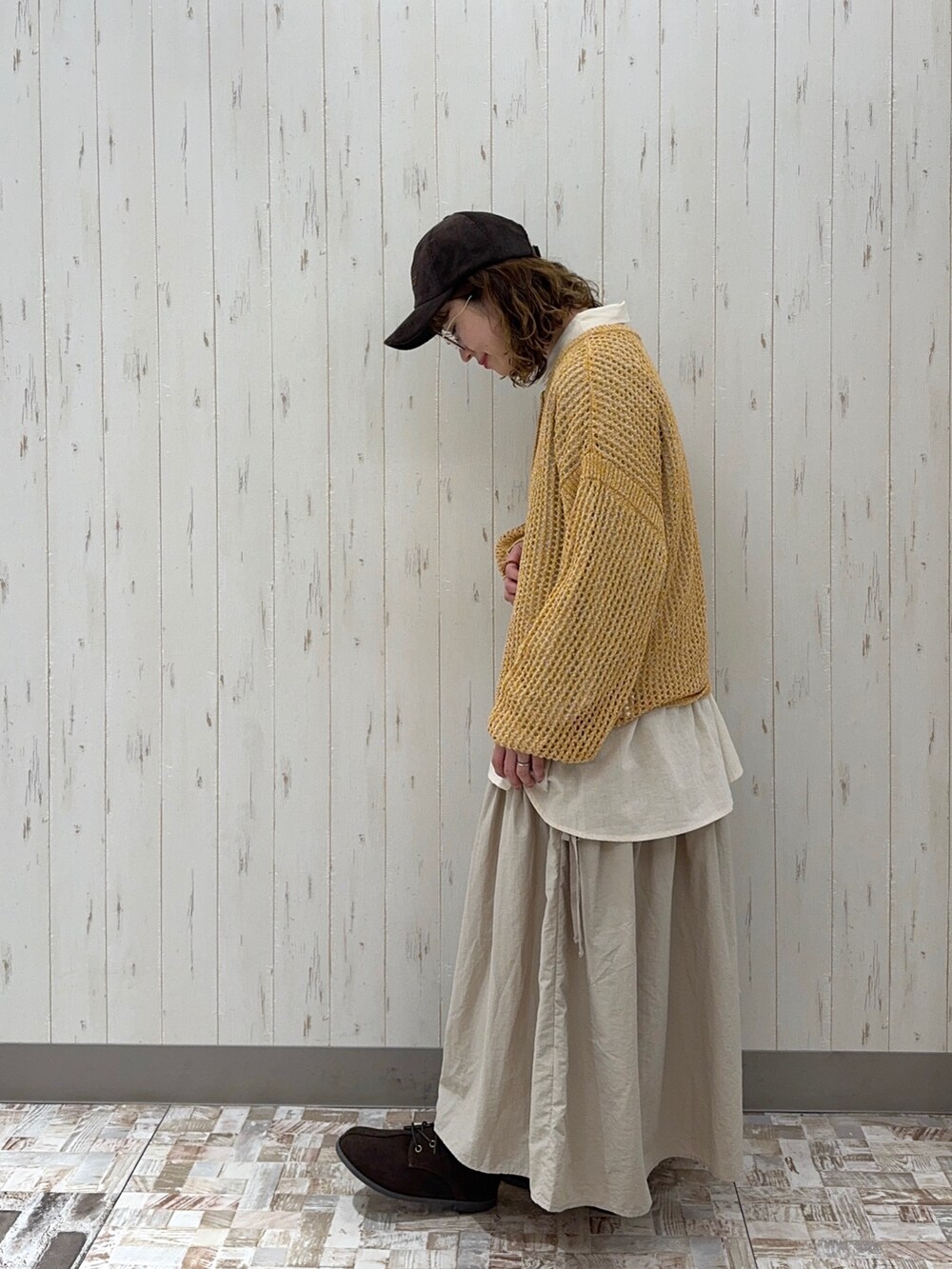 イエロー系のニット/セーター、ホワイト系のシャツ/ブラウス、ベージュ系のスカートを着用したレディースの秋コーディネートの2枚目の写真