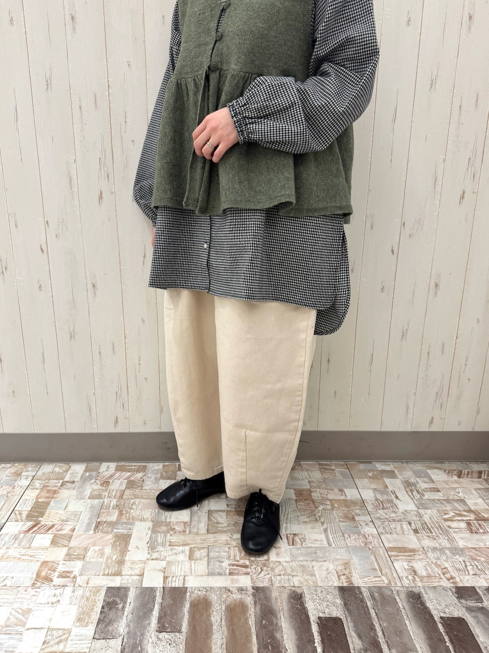 グリーン系のベスト、ブラック系のチュニック、ホワイト系のその他パンツを着用したレディースの春コーディネートの3枚目の写真