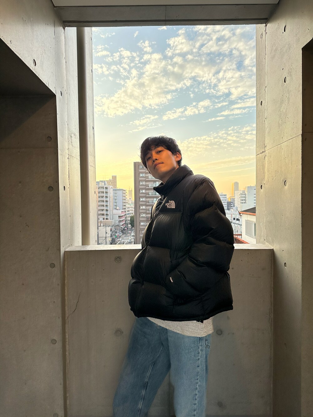 ブルー系のデニムパンツ、ベージュ系のスニーカー、ブラック系のダウンジャケット/コートを着用したメンズの秋コーディネートの5枚目の写真